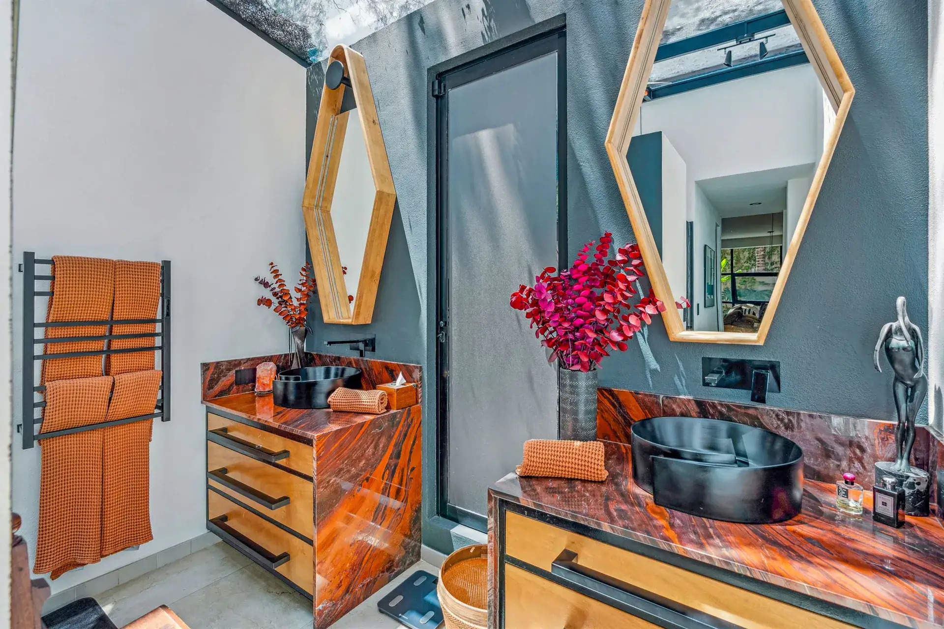 Villa Pacifica, bathroom with a hexagonal wood-framed mirror, a black vessel sink and an orange towel, San Miguel de Allende
