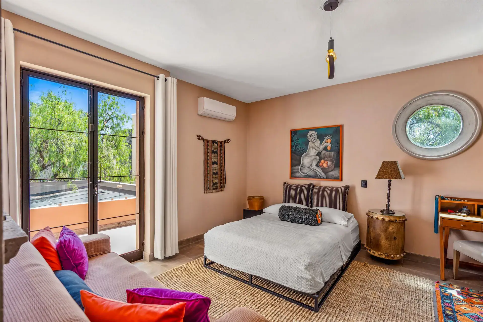 Villa Pacifica, bedroom with pink walls, a platform bed, a round window and a pink sofa, San Miguel de Allende