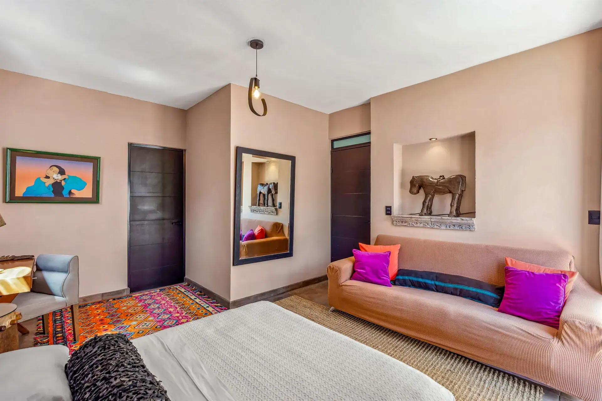 Villa Pacifica, bedroom with a pink sofa, a mirrored niche and a framed horse sculpture, San Miguel de Allende