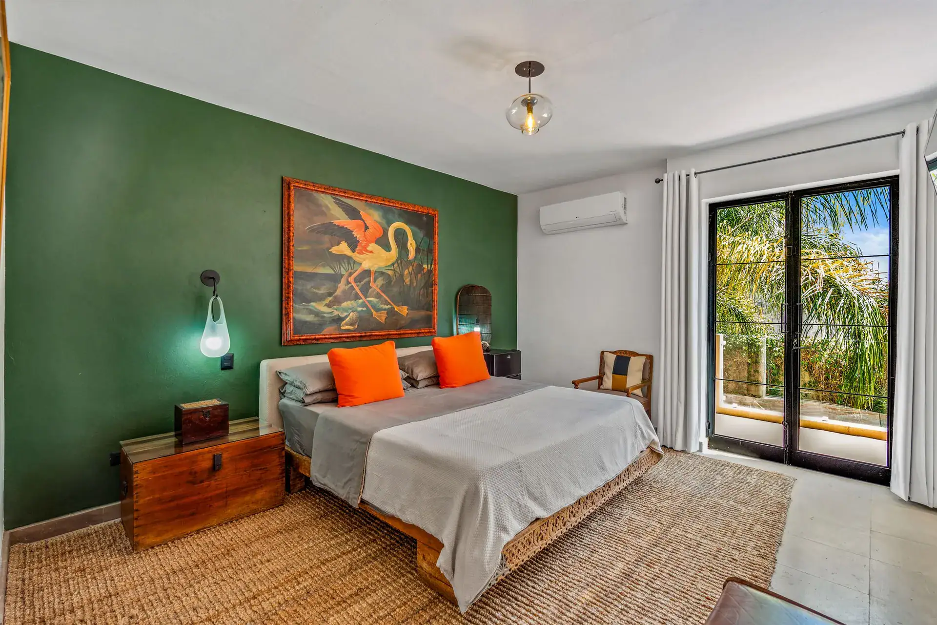 Villa Pacifica, bedroom with a green wall, a large framed flamingo painting and orange pillows, San Miguel de Allende