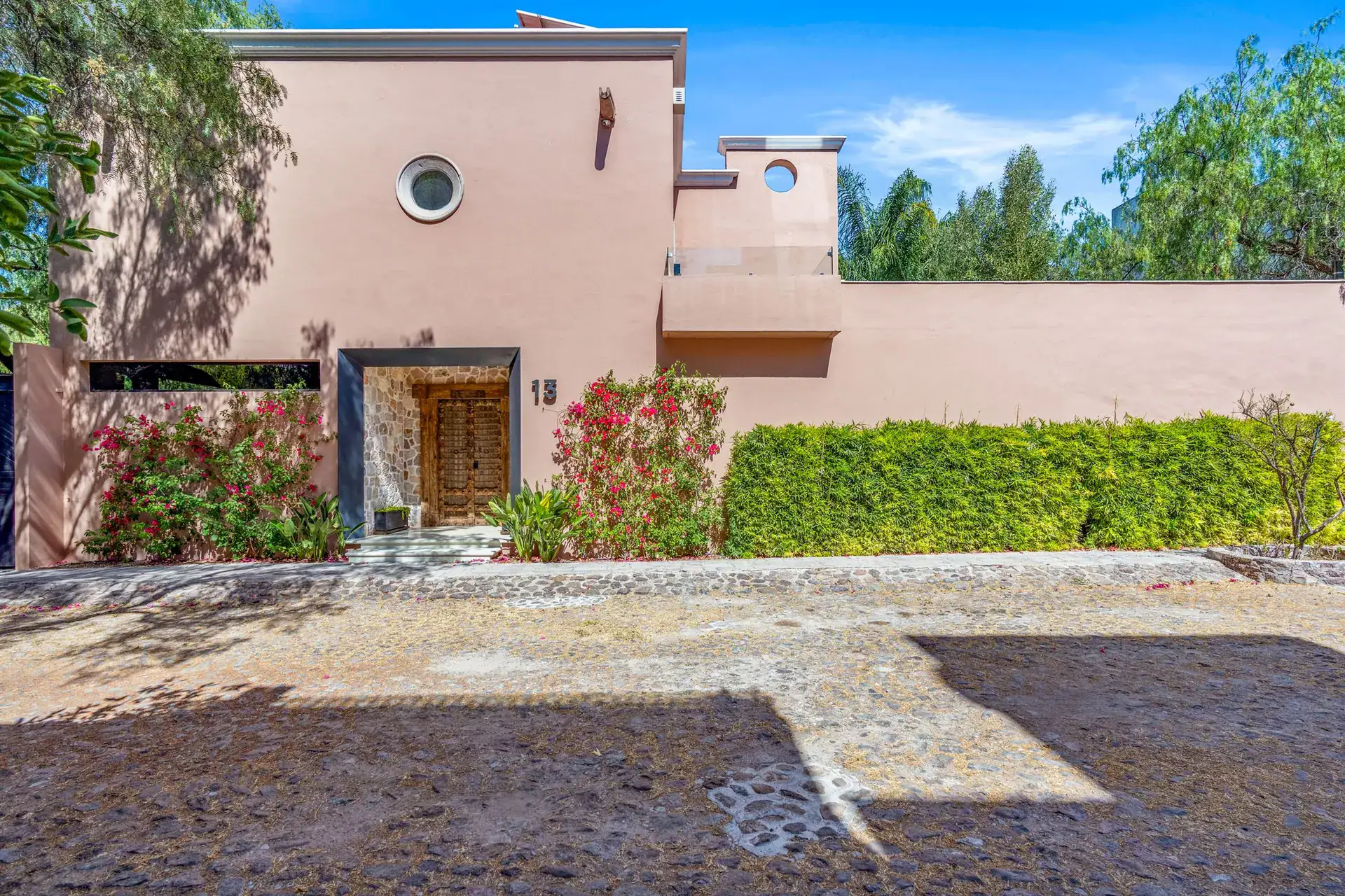 Villa Pacifica, street entrance with a pink wall, a stone-framed gate and a hedge, San Miguel de Allende