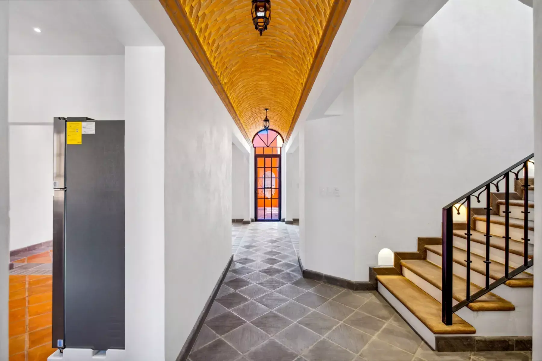 Villa Picasso, entry hallway with a brick vaulted ceiling, a diamond-pattern slate floor and a staircase with a black iron railing, San Miguel de Allende