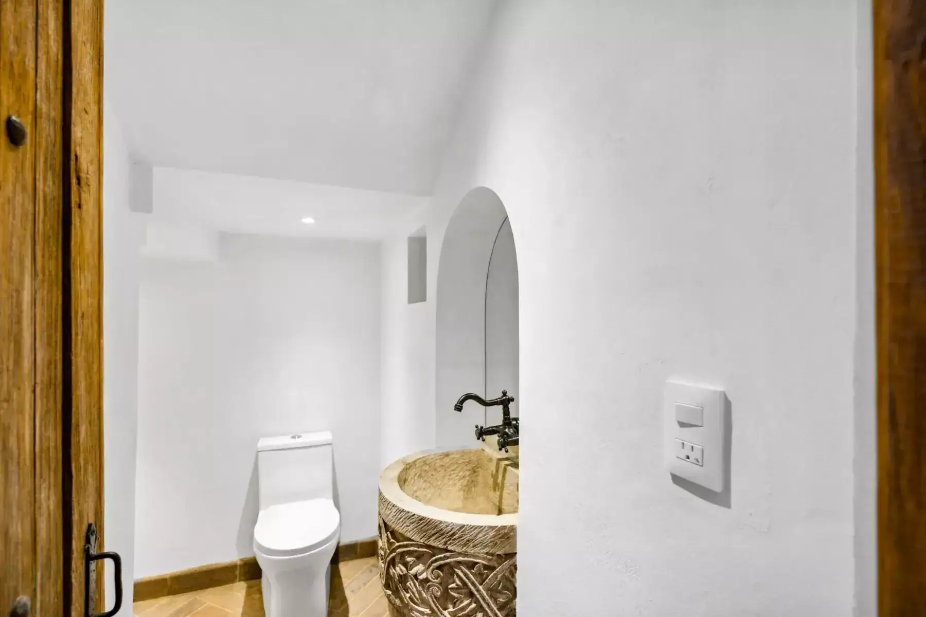 Villa Picasso, powder room with a carved stone sink, a bronze tap and an arched niche, San Miguel de Allende