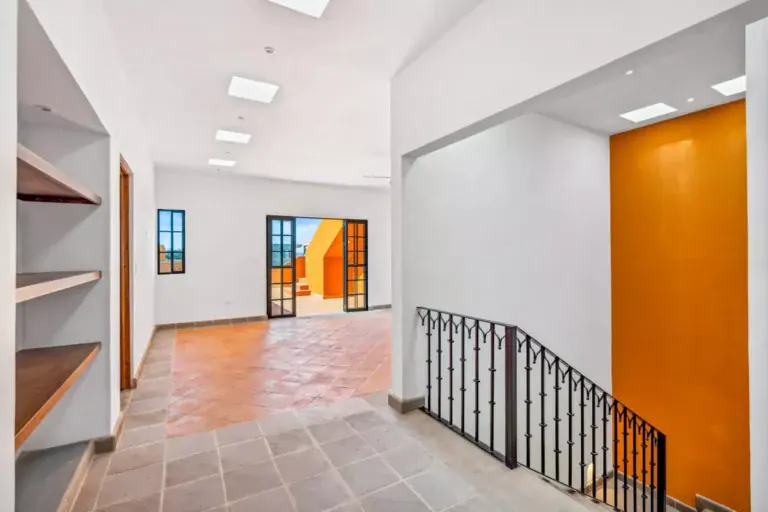 Villa Picasso, empty room with built-in shelves, a black iron stair railing and an orange accent wall, San Miguel de Allende