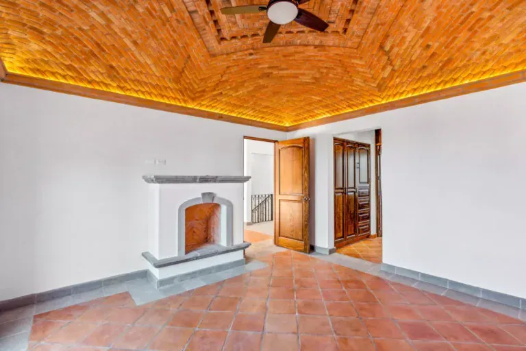 Villa Picasso, empty room with a brick vaulted ceiling with lighting, a stone fireplace and a wood door, San Miguel de Allende