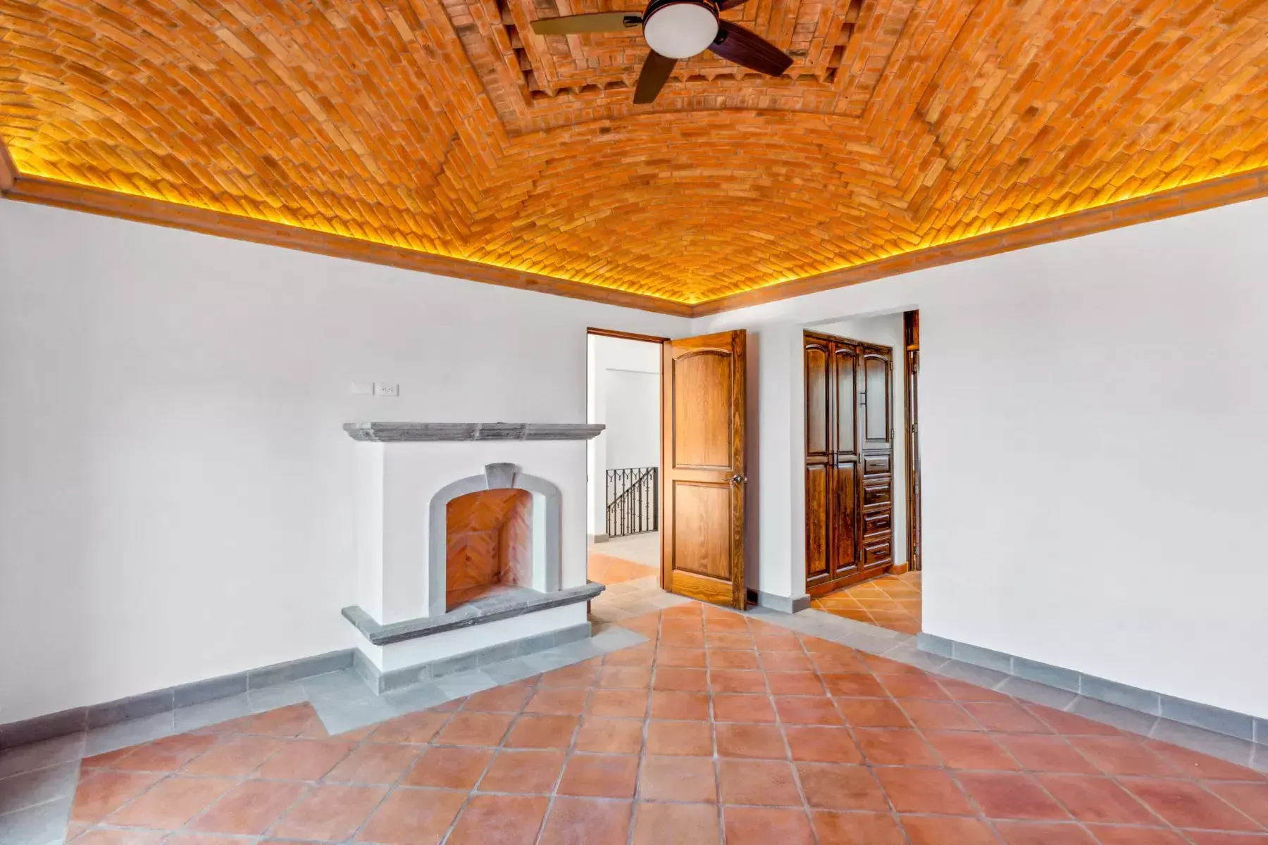 Villa Picasso, empty room with a brick vaulted ceiling with lighting, a stone fireplace and a wood door, San Miguel de Allende