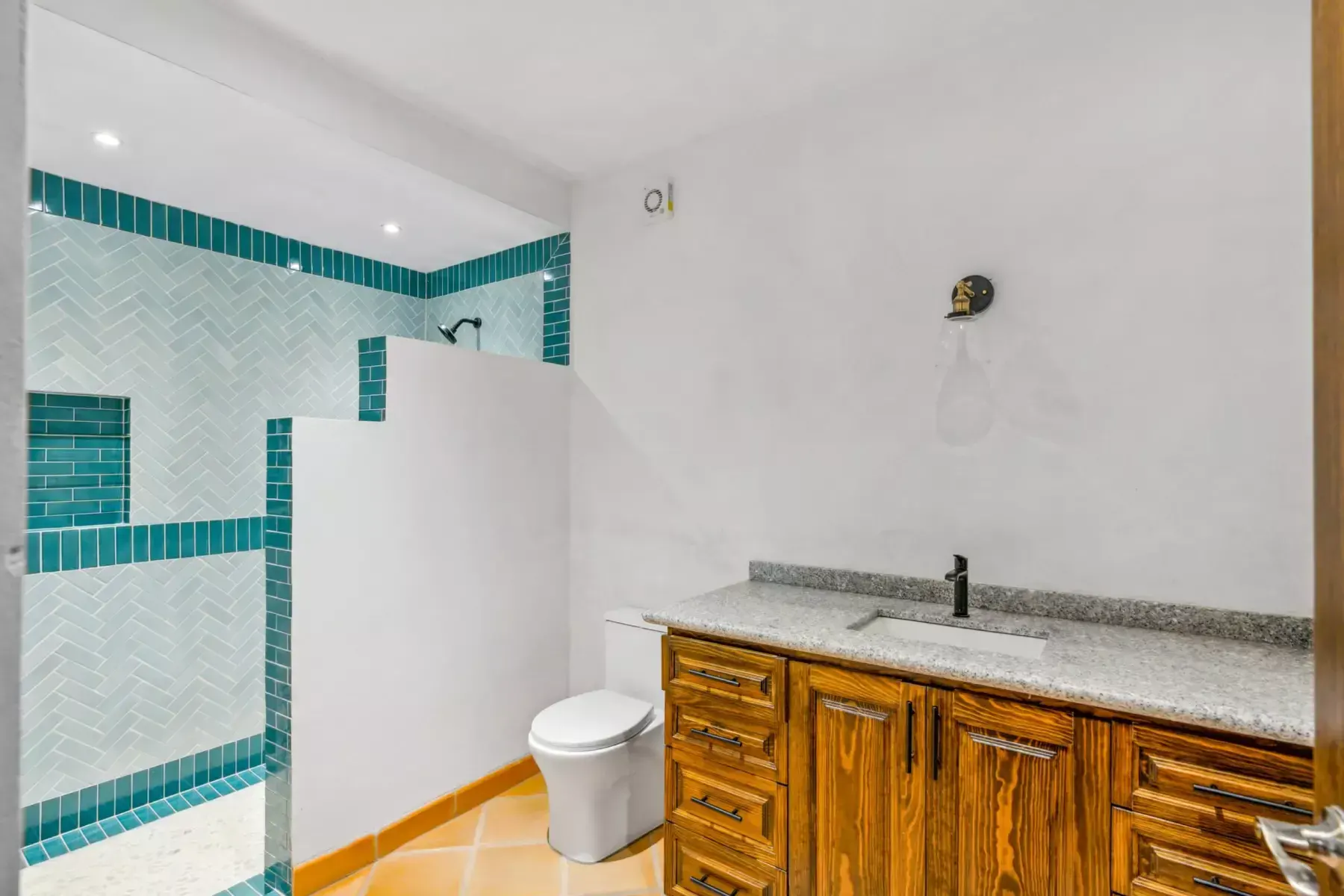 Villa Picasso, bathroom with a teal tile shower, a granite and wood vanity and a toilet, San Miguel de Allende