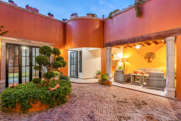 Villa Van Gogh, brick courtyard with a sculpted topiary and a covered terrace at dusk, San Miguel de Allende
