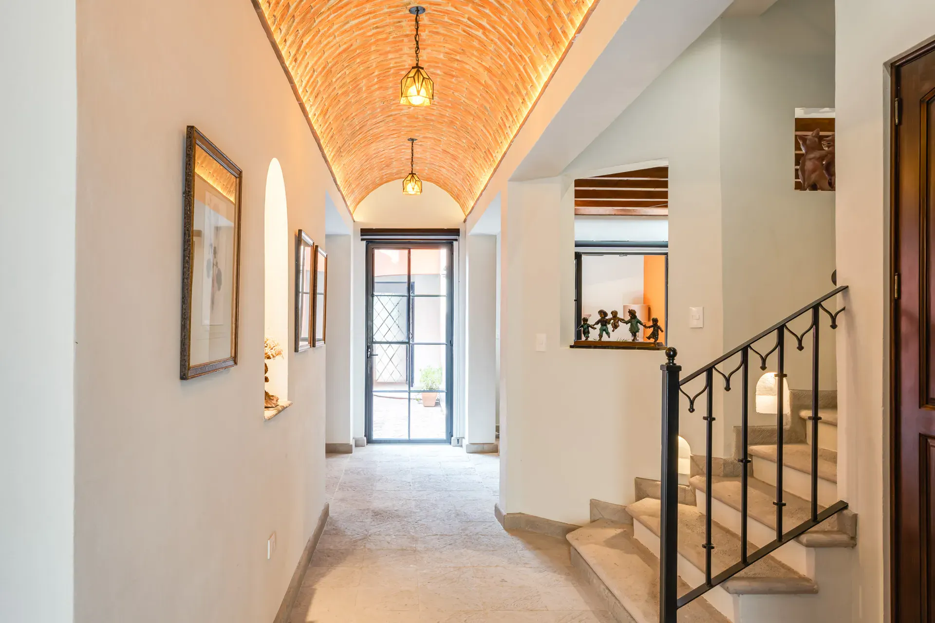 Villa Van Gogh, hallway with a brick vaulted ceiling leading to a glass door, San Miguel de Allende